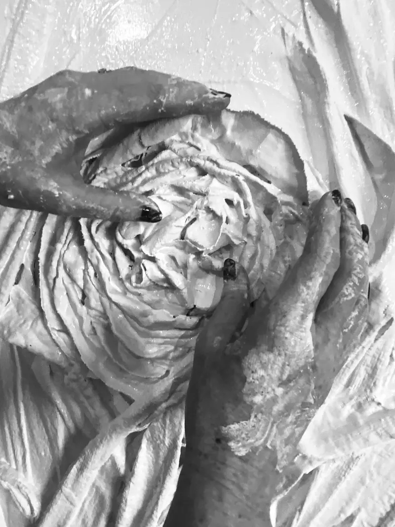 Mains sculptant un relief en matière blanche